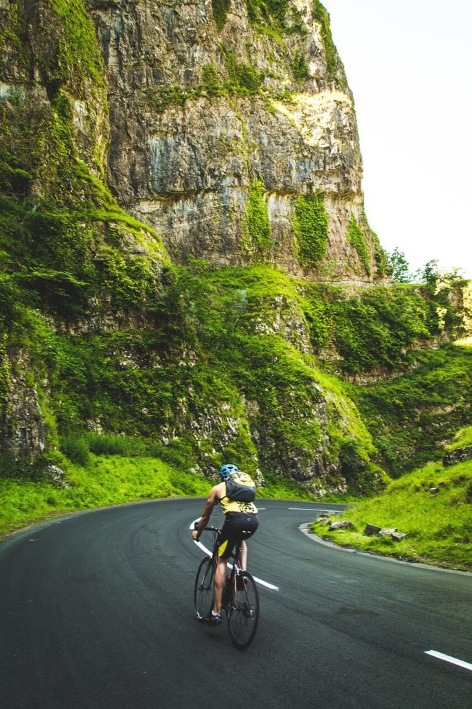 picture of cyclist on a roadway riding through mountains