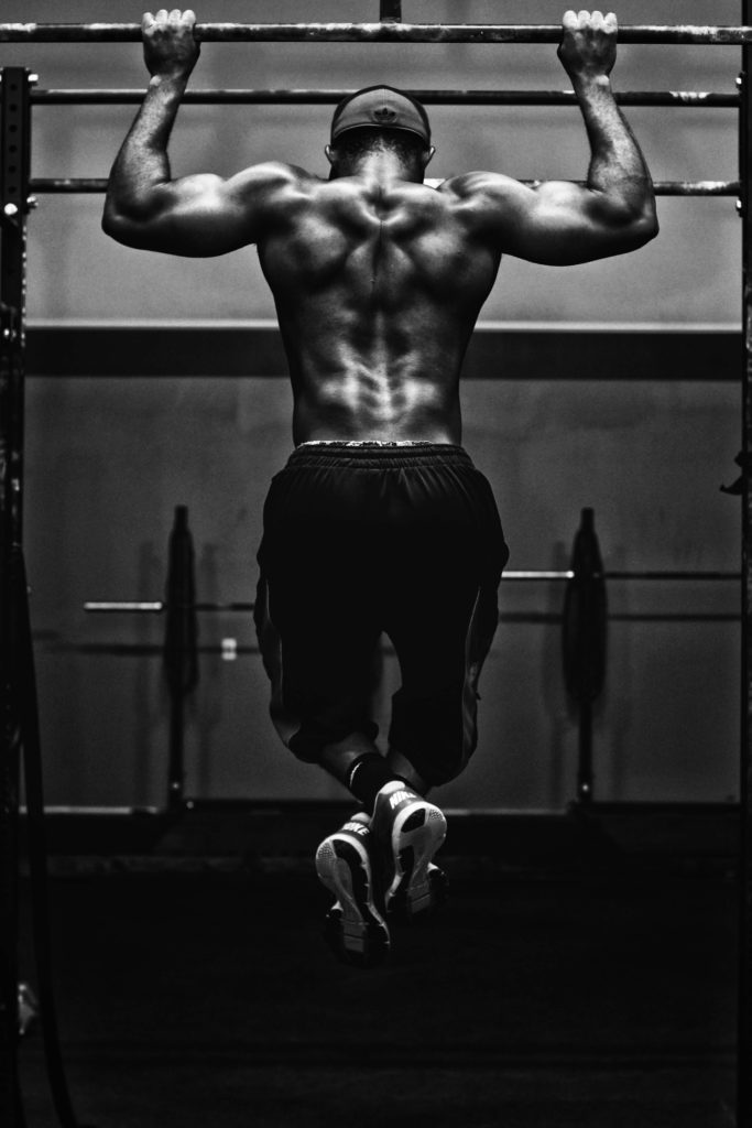 Black and white picture of male athlete doing pull ups