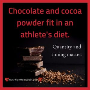 A stack of dark chocolate bars sit in a pile of cocoa and chocolate shavings. Text indicates that athletes can safely consume chocolate and cocoa powder and still perform.